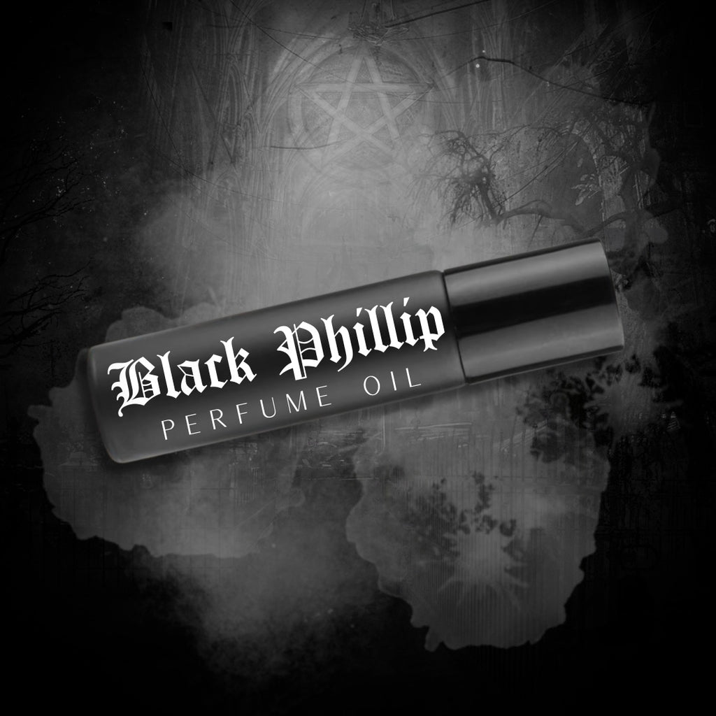 A roll-on bottle of Black Phillip Perfume Oil with sleek black label and silver accents. Surrounded by black lace and smoky shadows.