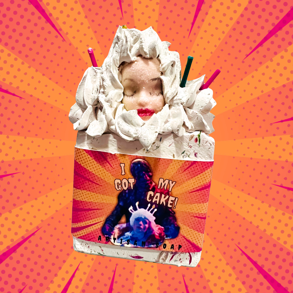 A horror-themed artisan soap inspired by the Creepshow episode “Father’s Day,” featuring a whipped soap frosting top, a creepy doll head, and birthday candle accents. The soap label reads “I Got My Cake!” with an image of the iconic zombie character from the movie holding a decapitated head like a cake. The background is a retro comic-style pop art burst. Spooky novelty soap for horror fans and collectors.