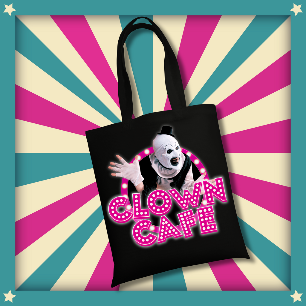 A black cotton tote bag with the same Clown Café neon marquee design and Art the Clown graphic, displayed on a retro carnival-style background.
