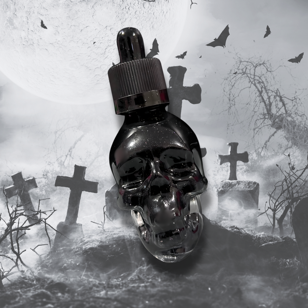 A dark, skull-shaped bottle of shimmering bath and body oil lies on a misty graveyard backdrop with crosses and bats in the sky. The product is called Kiss of Vampira and is scented with dark berry, gothic rose, and damp earth.