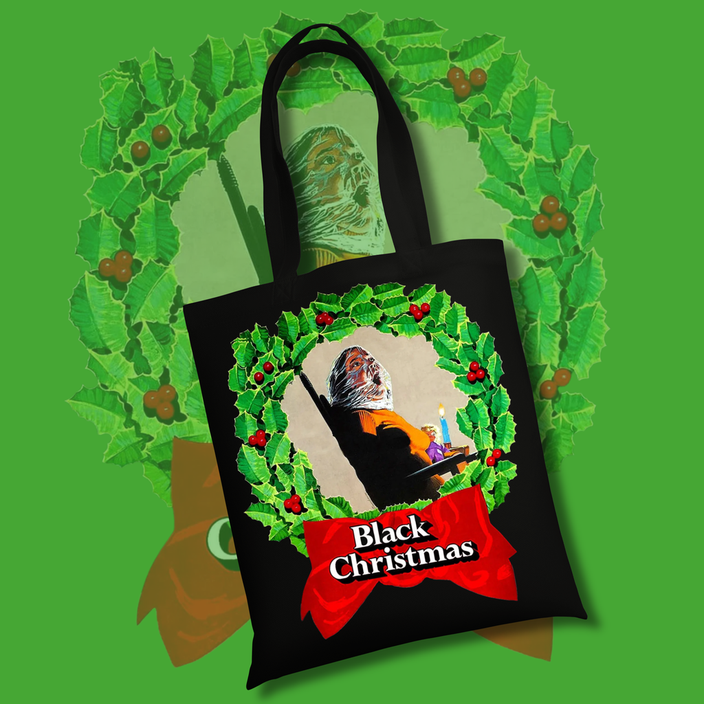 Black tote bag featuring a slasher figure inside a Christmas wreath with red “Black Christmas” banner inspired by the 1974 horror film.