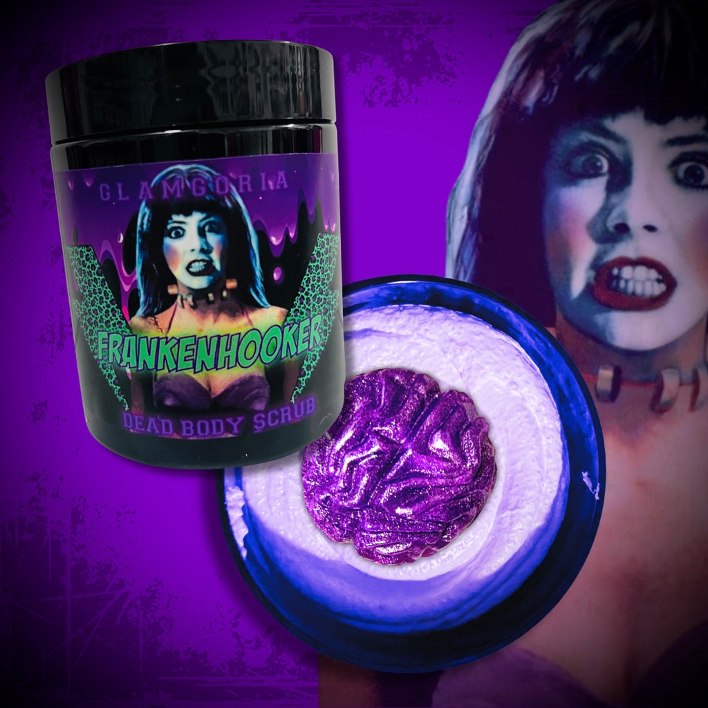 A jar of Glamgoria’s Frankenhooker Brain Candy Dead Body Scrub with neon-green “Frankenhooker” text and a retro horror-style image of the titular character. Beside it is an open jar revealing vibrant purple whipped scrub, all set against a vivid purple background with a distressed texture and a close-up of Frankenhooker’s shocked face.
