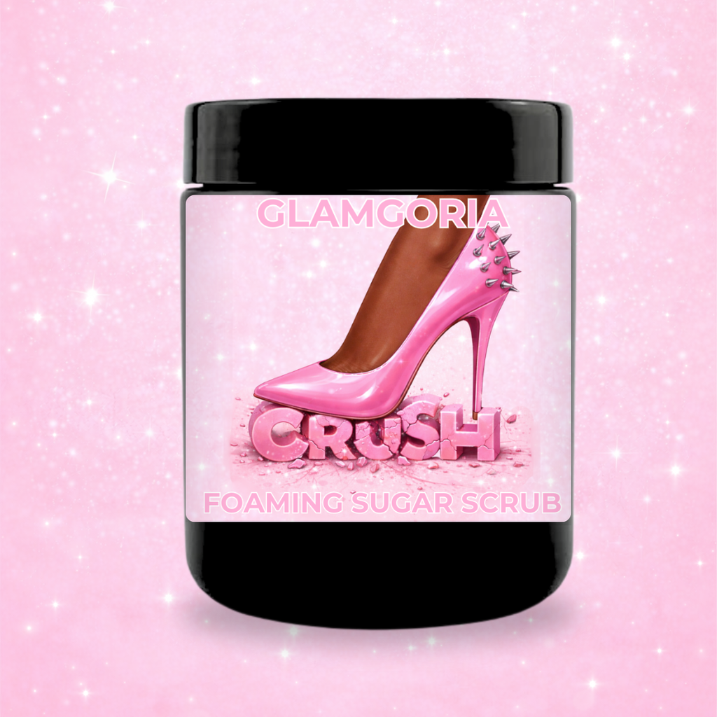 CRUSH foaming sugar scrub in a black jar with a pink label showing a spiked high heel crushing the word “crush” on a soft pink sparkle background.
