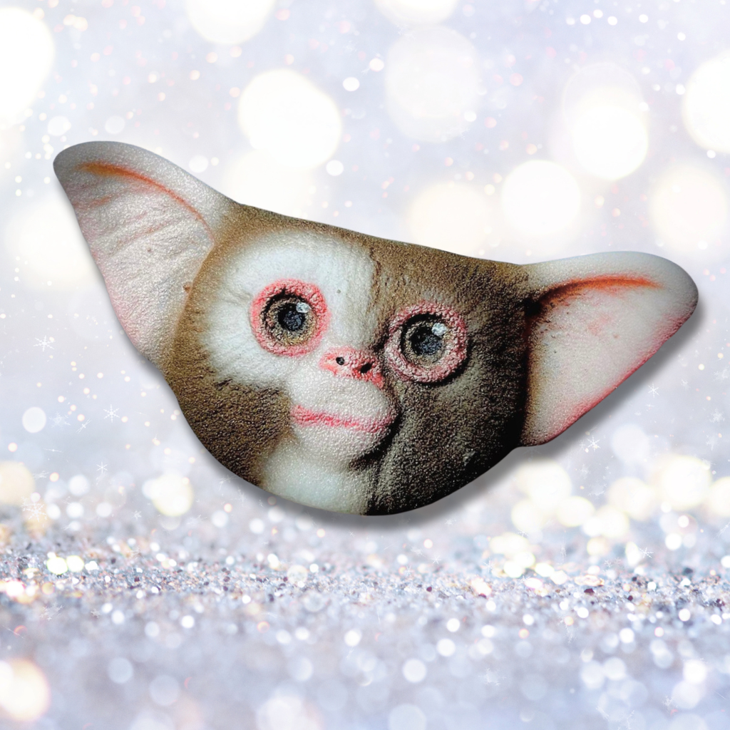 Hand-painted mogwai-inspired bath bomb with big eyes and large ears on a sparkling winter background