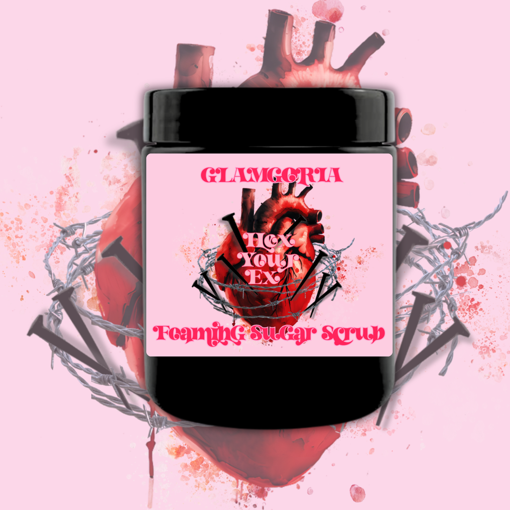 Hex Your Ex foaming sugar scrub in a black jar with a pink label featuring an anatomical heart wrapped in barbed wire and nails on a soft pink background.