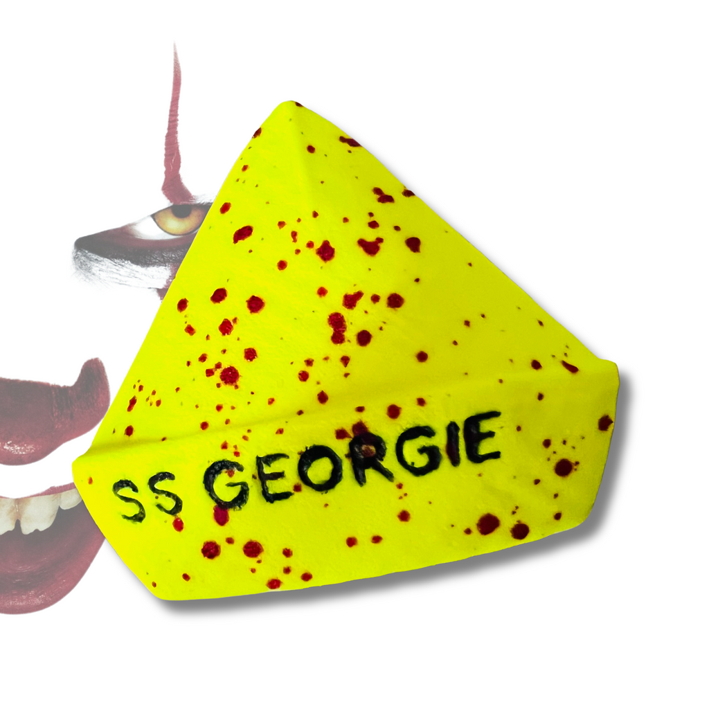 A yellow paper-boat-shaped bath bomb with red splatters and the words “SS GEORGIE” written on the side, inspired by IT.