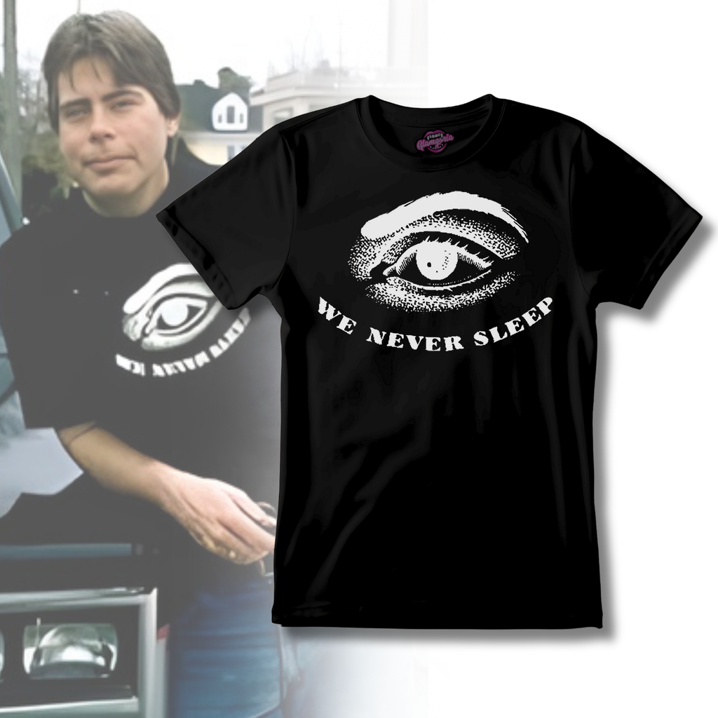 Black unisex t-shirt featuring a white illustrated eye graphic with the phrase “We Never Sleep” curved beneath it.