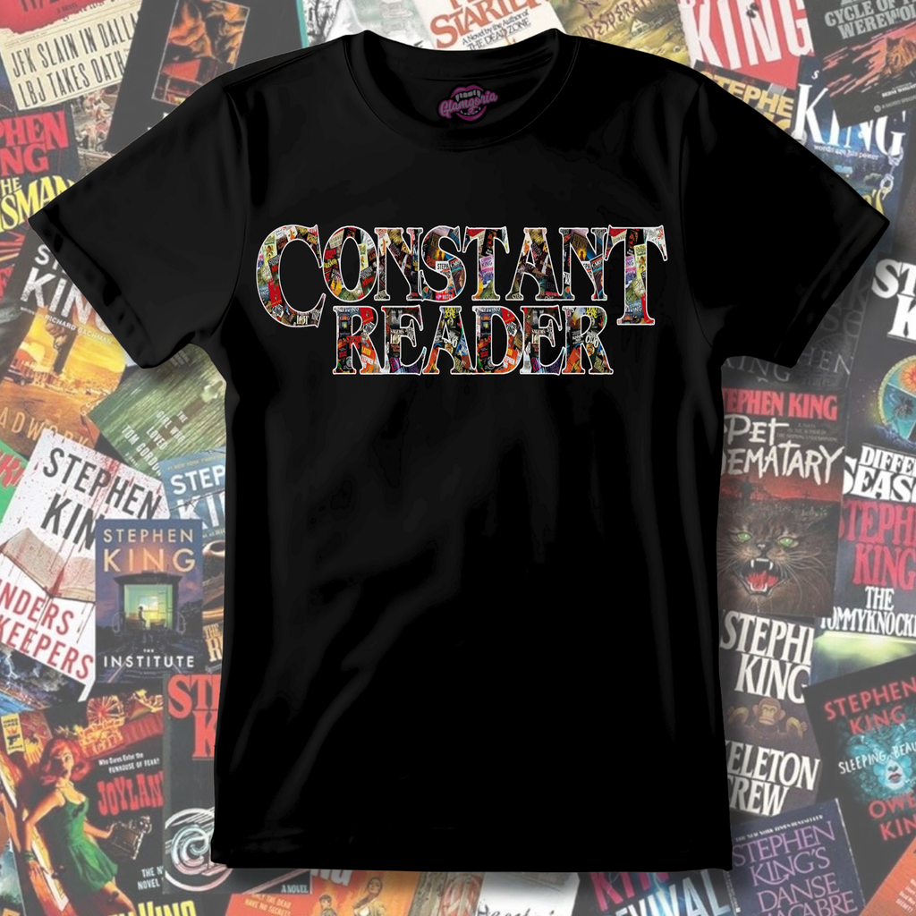 Black t-shirt featuring the phrase “Constant Reader” in large lettering filled with a collage of Stephen King book cover imagery.
