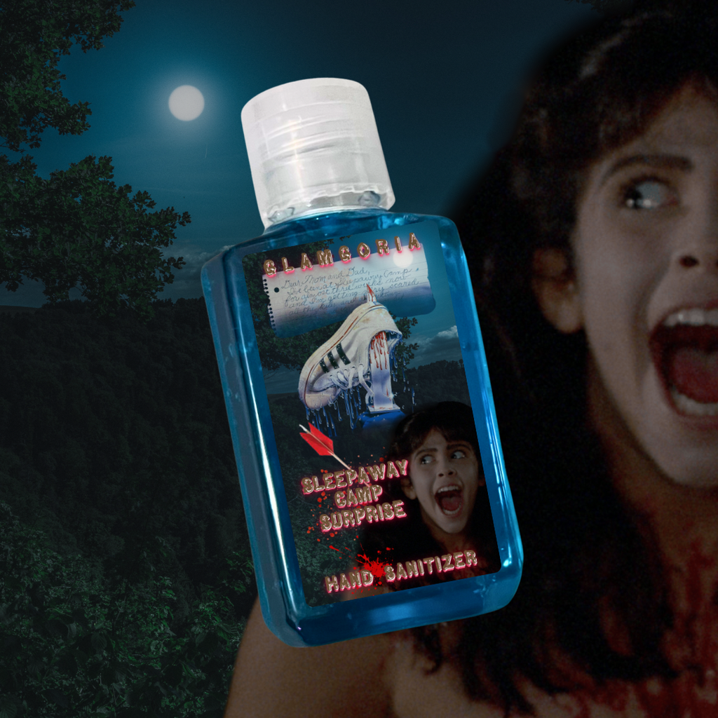 “Blue travel-sized hand sanitizer bottle with a horror-themed label inspired by Sleepaway Camp. The label features a bloody sneaker, a moonlit forest, and a screaming face of a character from the film. Glamgoria branding appears at the top.”