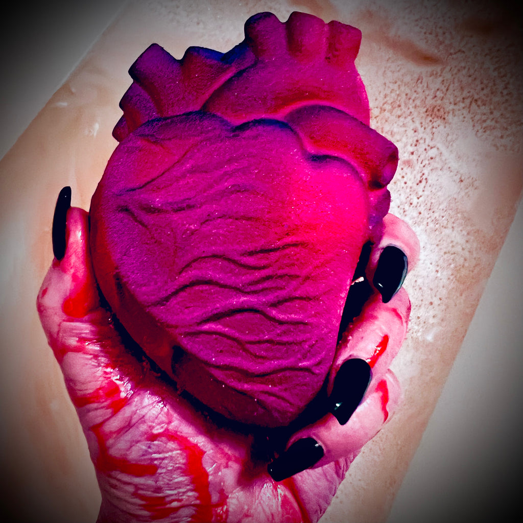 An anatomical heart-shaped bath bomb in deep pink and red, styled to resemble a realistic heart, inspired by the horror film My Bloody Valentine.